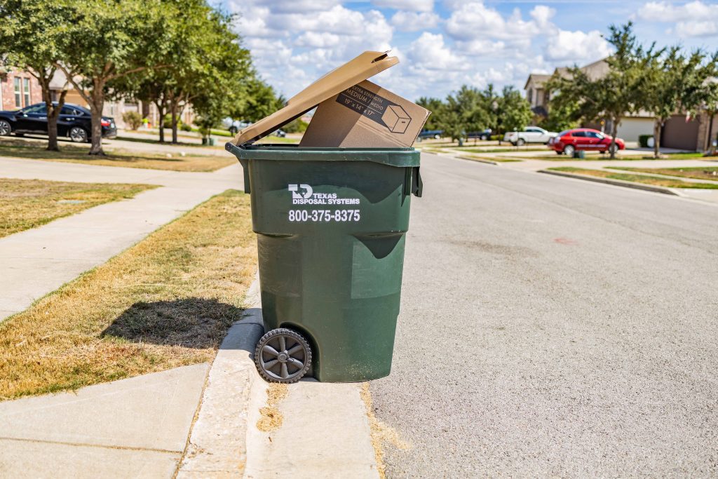 TDS garbage bin overloaded with cardboard box on curbside