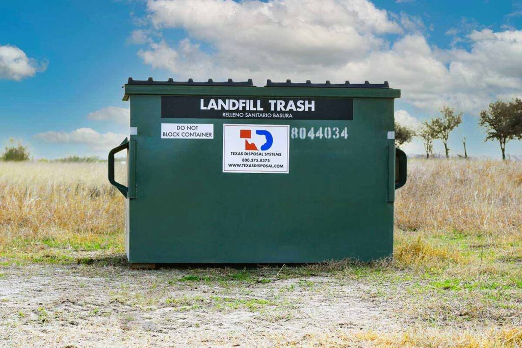 TDS green 4 yard front dumpster for landfill trash sitting in field