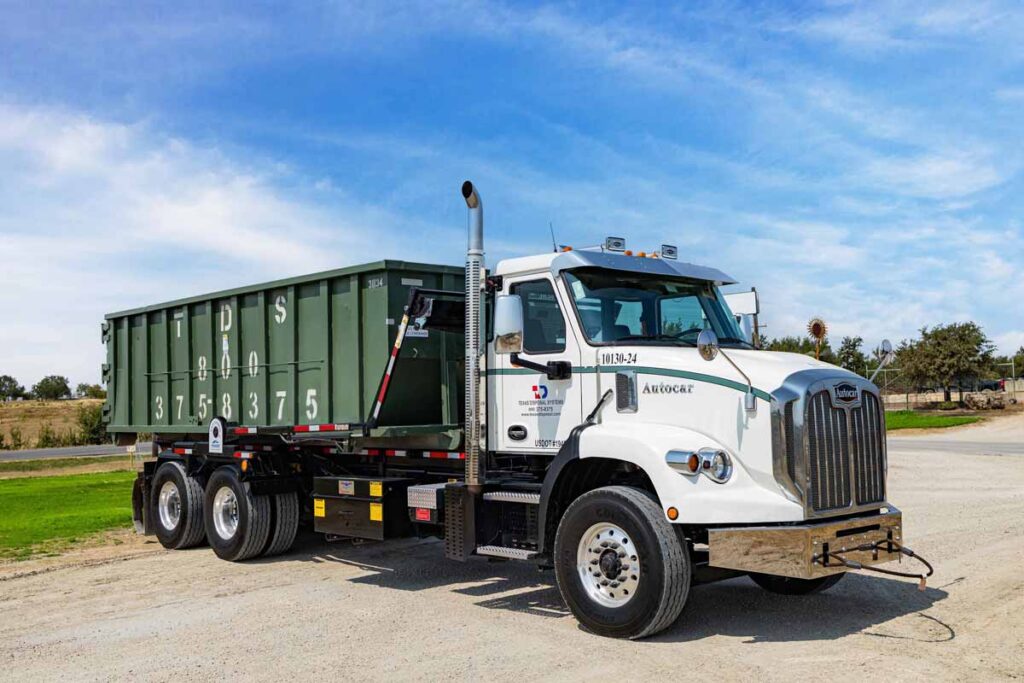 Green Roll off dumpster on TDS truck parked under blue sky