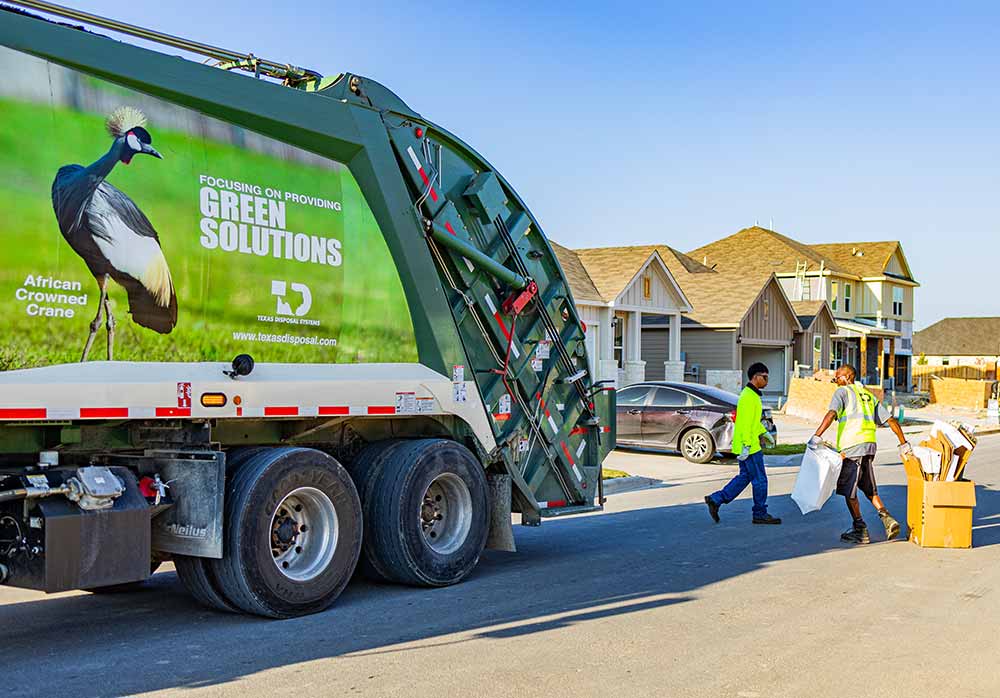 TDS trash truck with two employees putting things into the truck