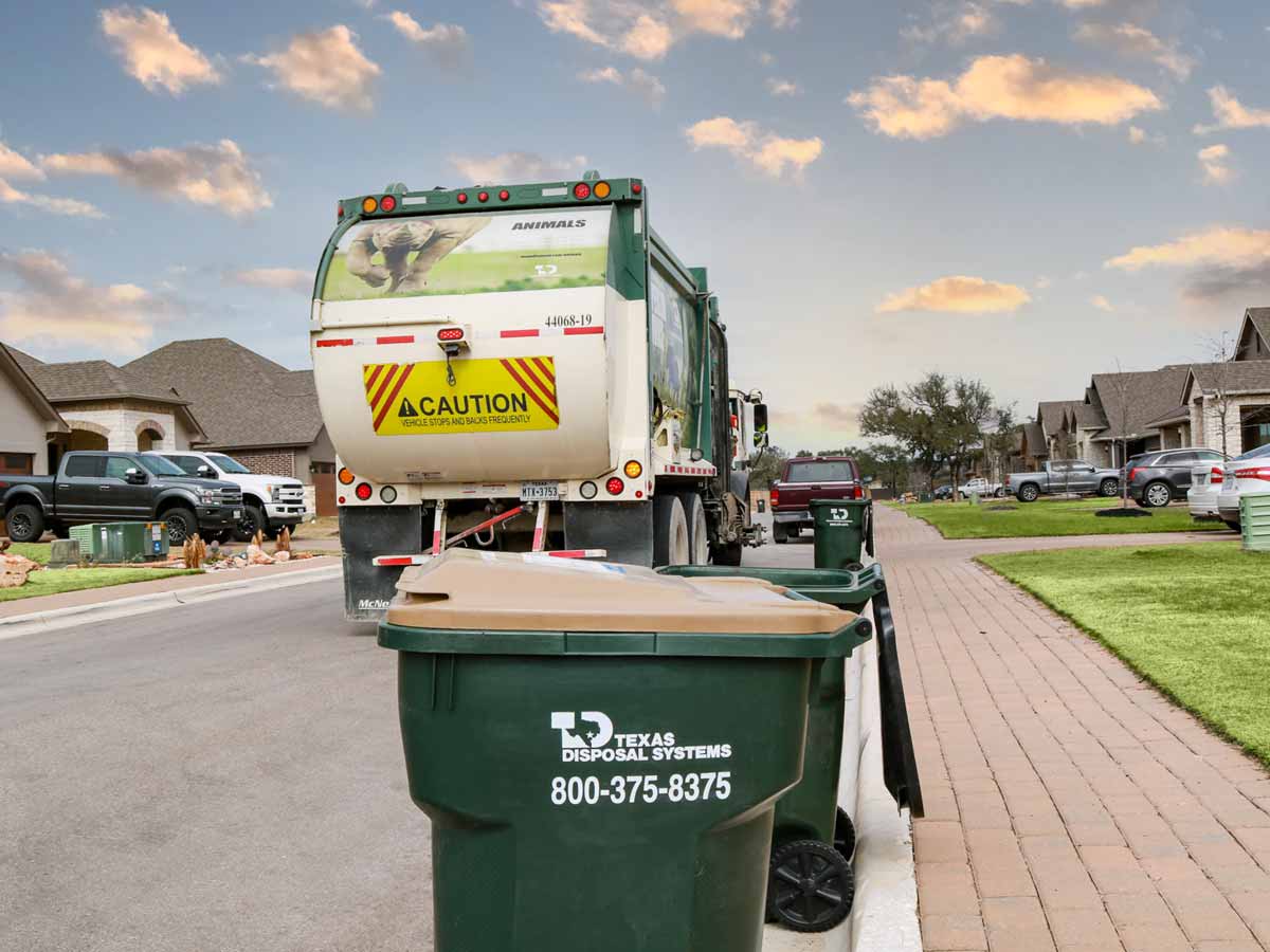 Texas Disposal Systems recycle bin with company logo and phone number painted on it.