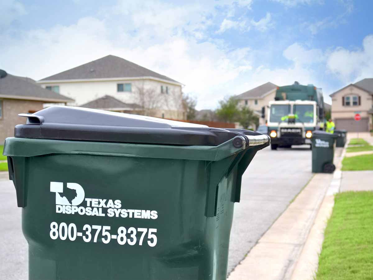 Texas Disposal Systems waste bin with company logo and phone number painted on it.