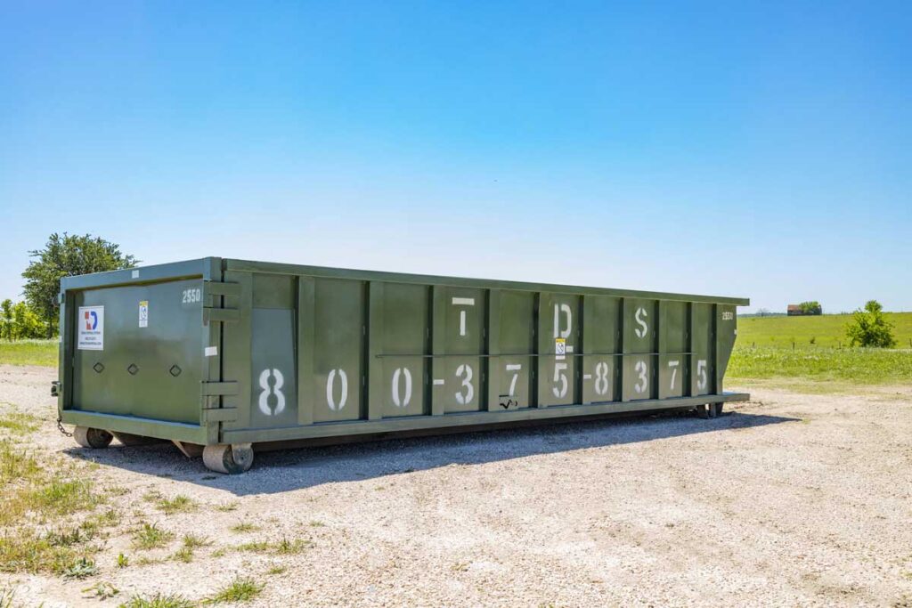 Green 20 Yard TDS Roll Off Dumpster parked in field