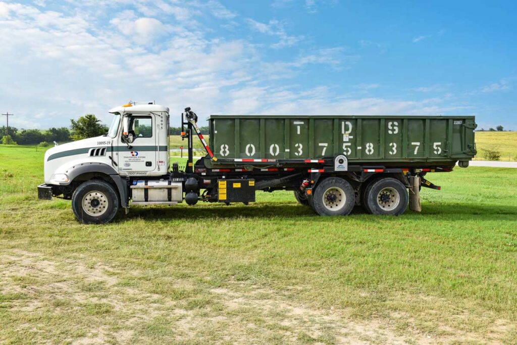 Green 20 yard TDS dumpster on back of TDS truck in field
