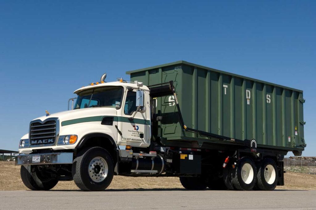 Green TDS roll of dumpster parked on TDS truck