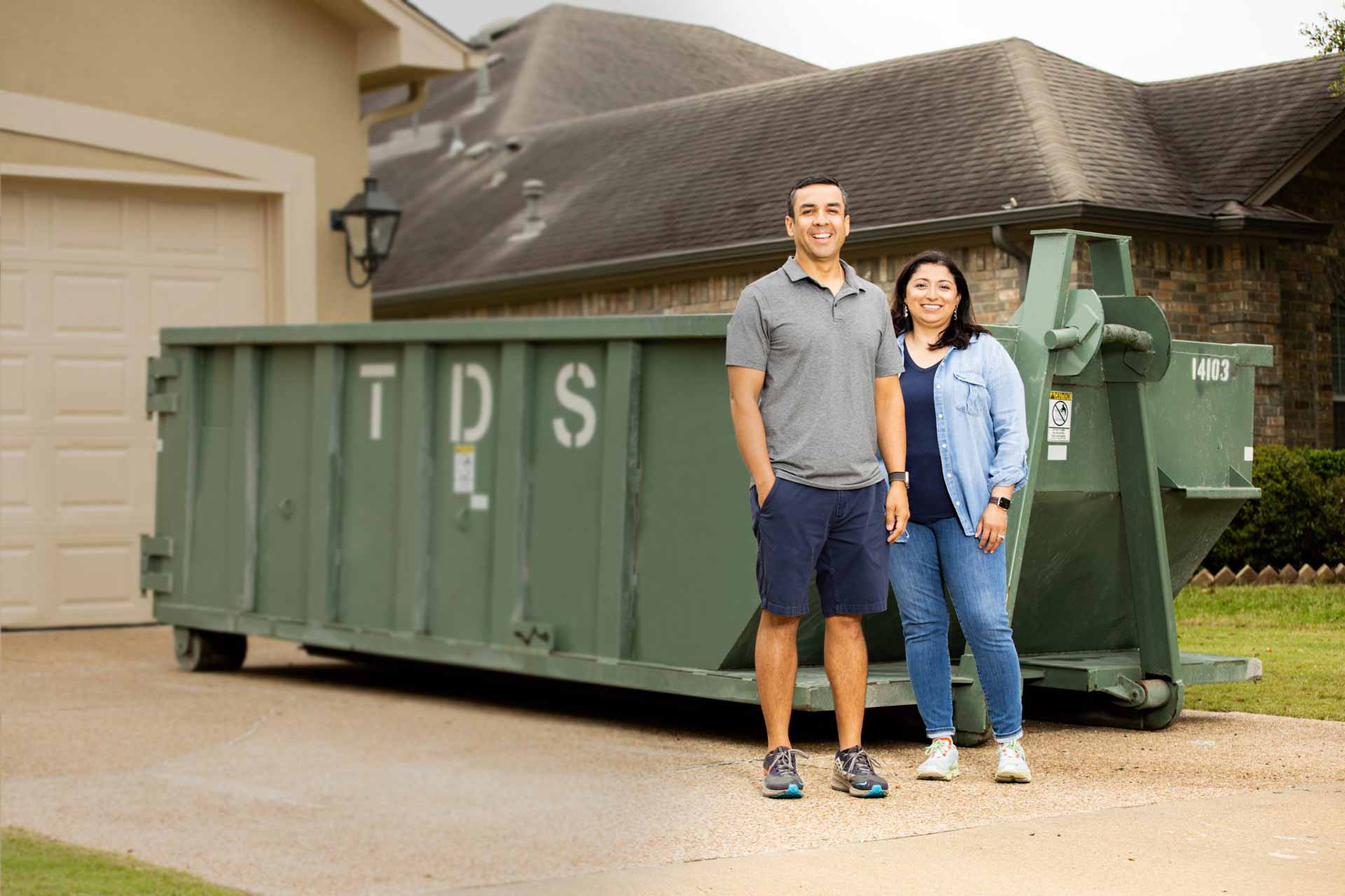 Green Residential mini roll off dumpster in front of house with couple standing in front
