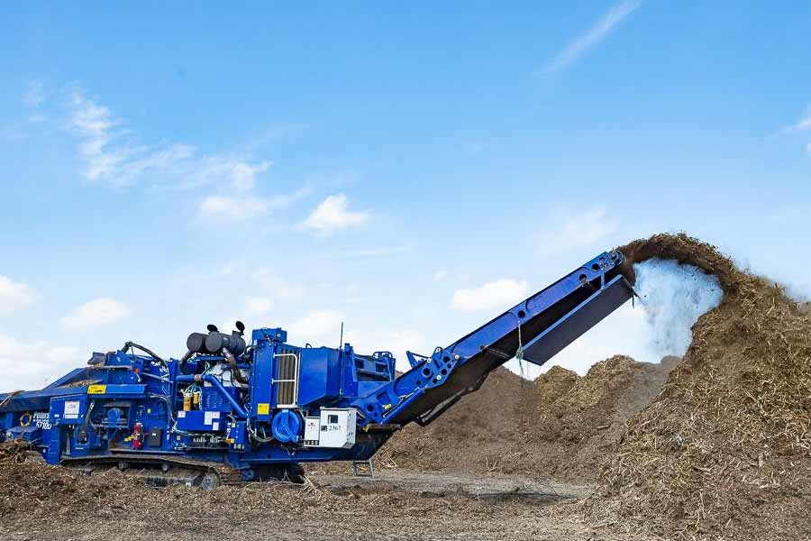 TDS blue composting grinder grinding up branches and wood into mulch