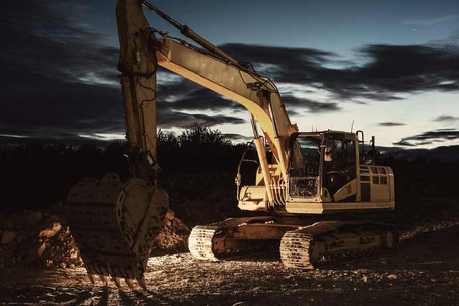 Large excavator at night on a construction site with minimal lights illuminating it