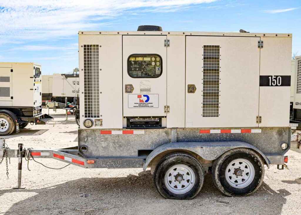 A tan generator sitting on a small trailer in a dirt lot