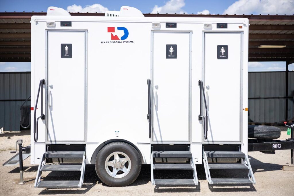 An extra wide portable restroom trailer with men and women’s door labels