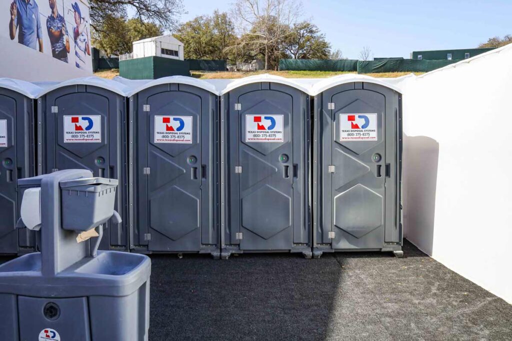 Grey TDS portable restrooms or porta potties at Dell Match Play with handwashing stations next to them