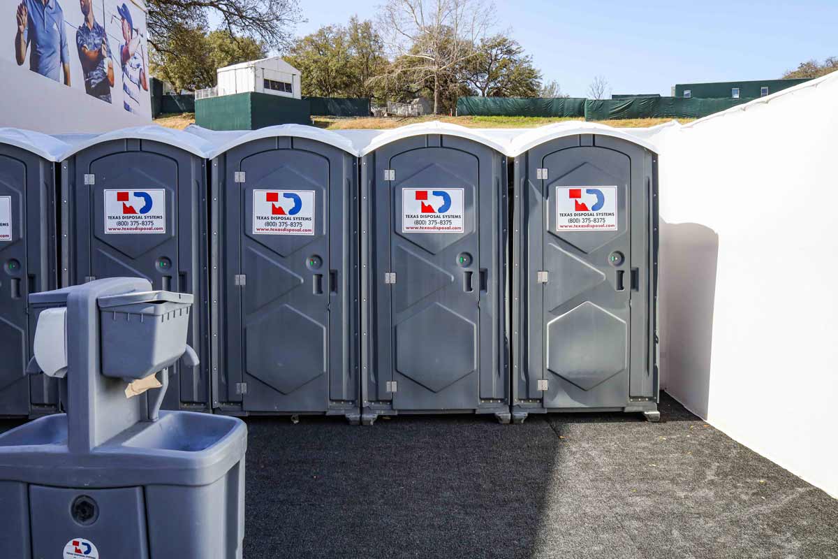 Grey TDS portable restrooms or porta potties at Dell Match Play with handwashing stations next to them