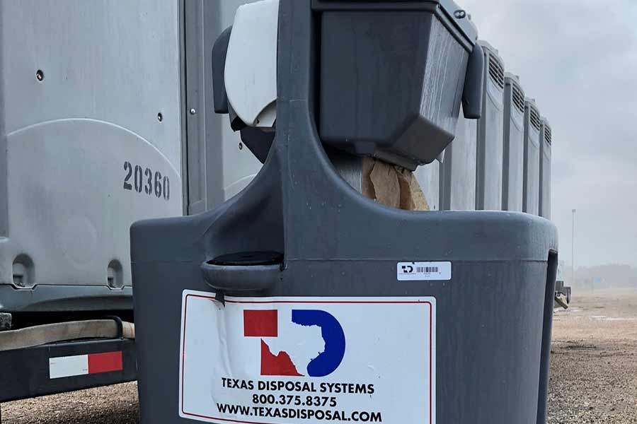 An individual handwashing station up close displaying the Texas Disposal Systems logo and contact information