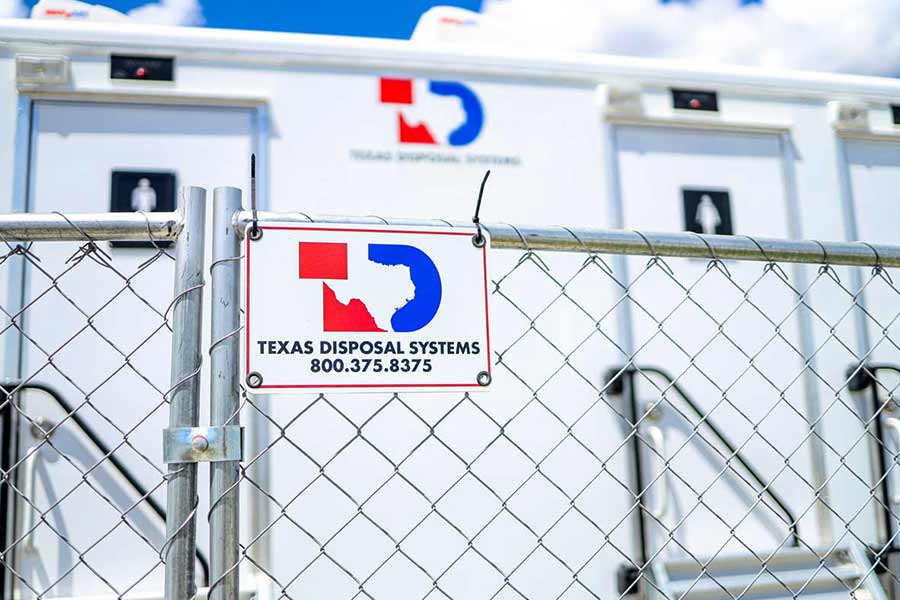White TDS restroom trailer with metal temporary fencing in front with red and blue TDS logo