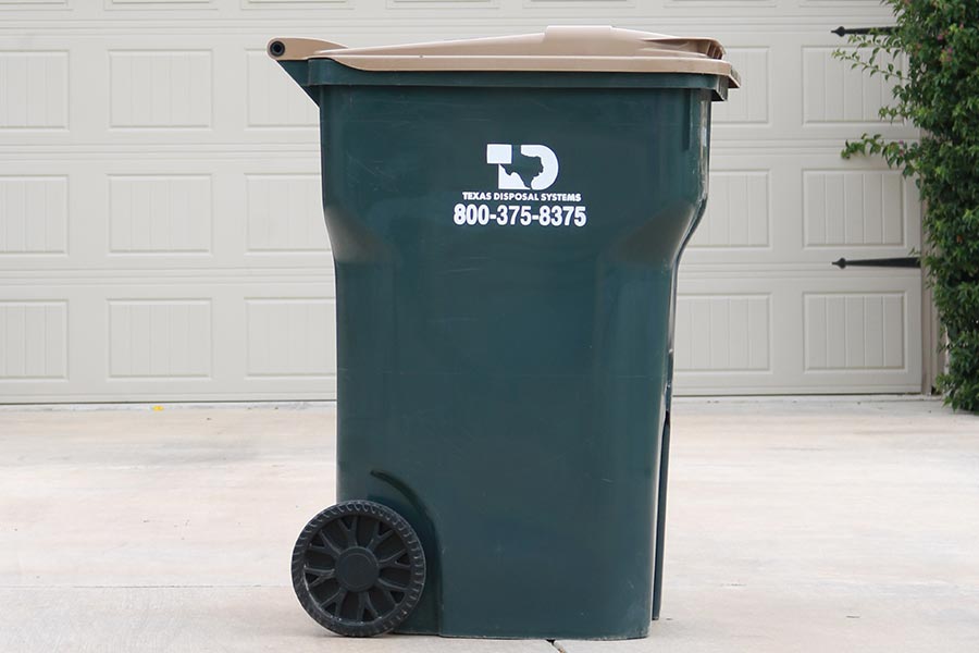 TDS green recycling cart with tan lid in front of garage door