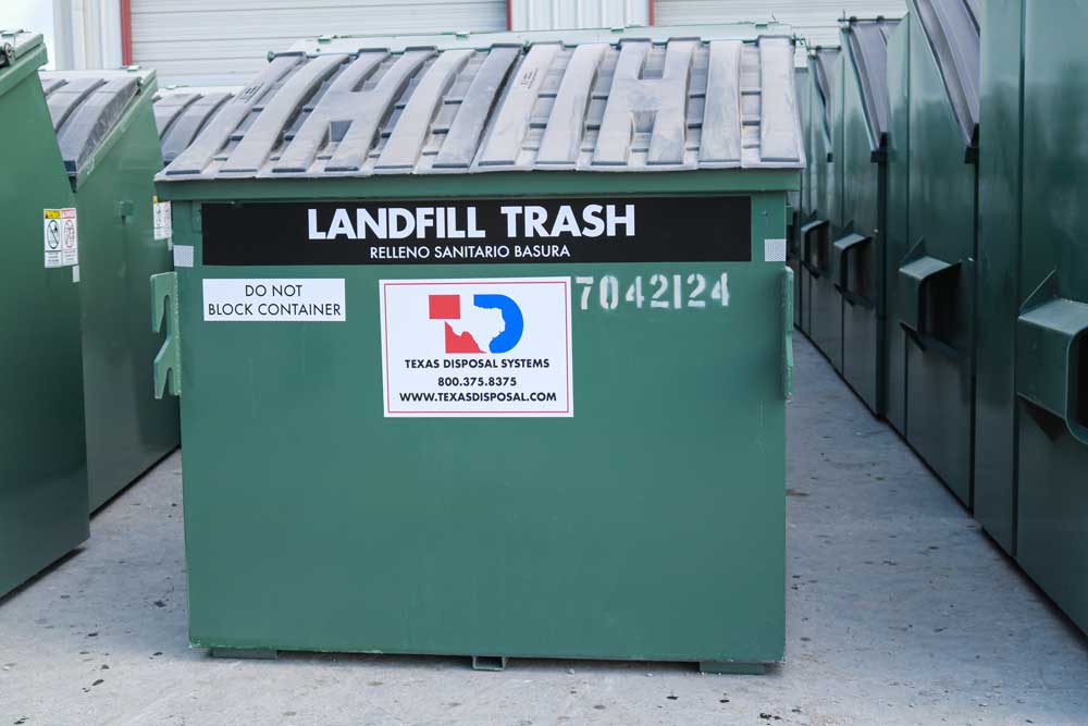 TDS green side load dumpster in a row of other dumpsters