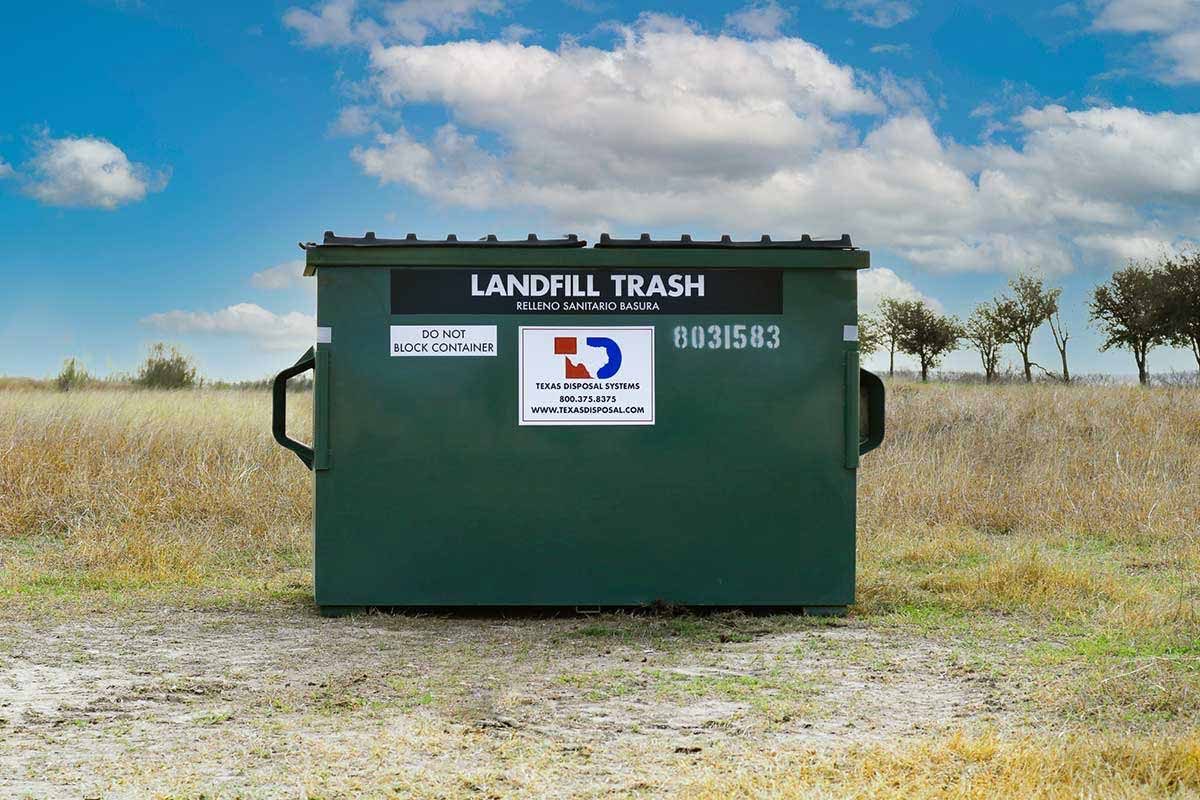 TDS green 3 yard front dumpster for landfill trash sitting in field